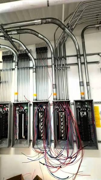 Multiple runs of steel conduit bending into a row of commercial distribution panels