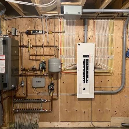 Mechanical room wall with electrical panel, conduit runs and adjacent boiler and manifold piping