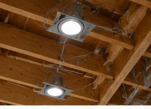 Recessed pot lights being installed in open ceiling joists during new construction rough-in